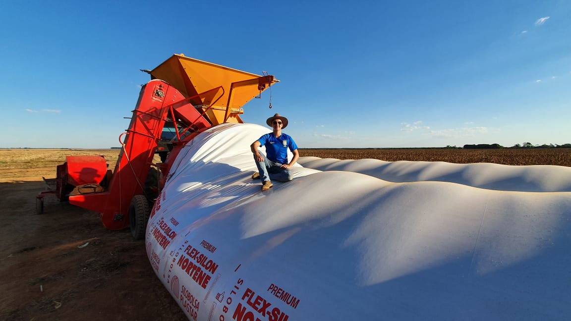 A foto de silos contém um homem sentado nos silos-bolsa de armazenagem de grãos