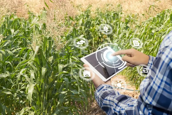 Homem operando o tablet através da tecnologia na agricultura com elementos digitais saindo da tela